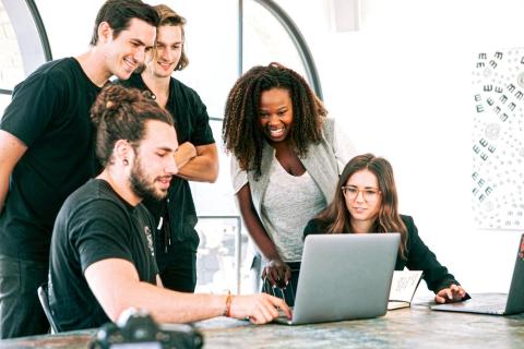 Team reviewing laptop screen while smiling